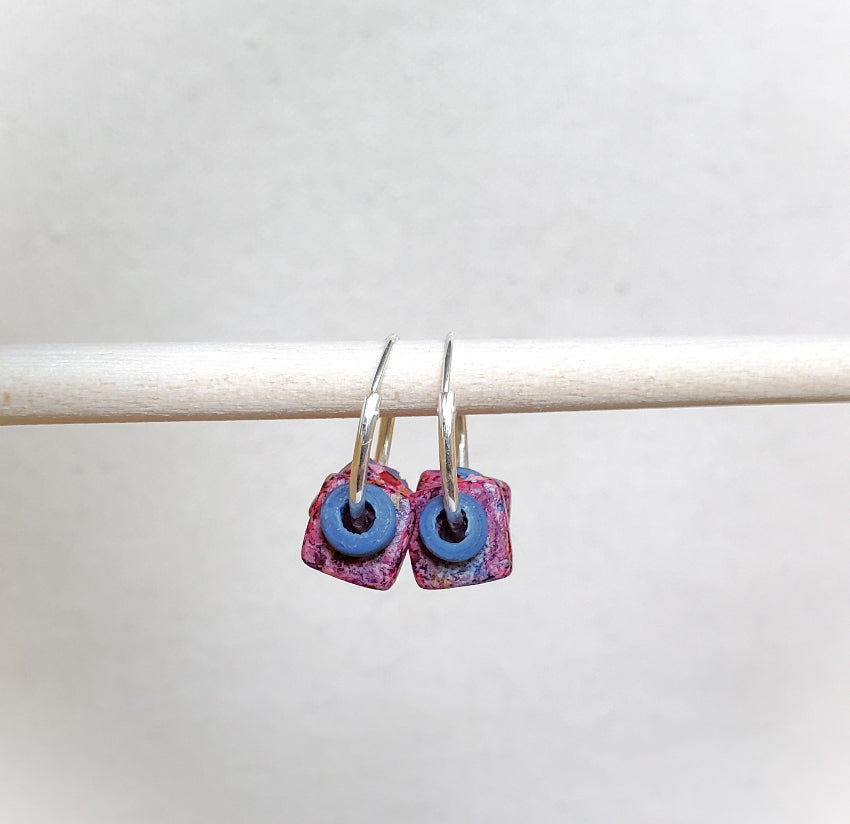 Pair of earrings with pink and blue circular designs on a white background