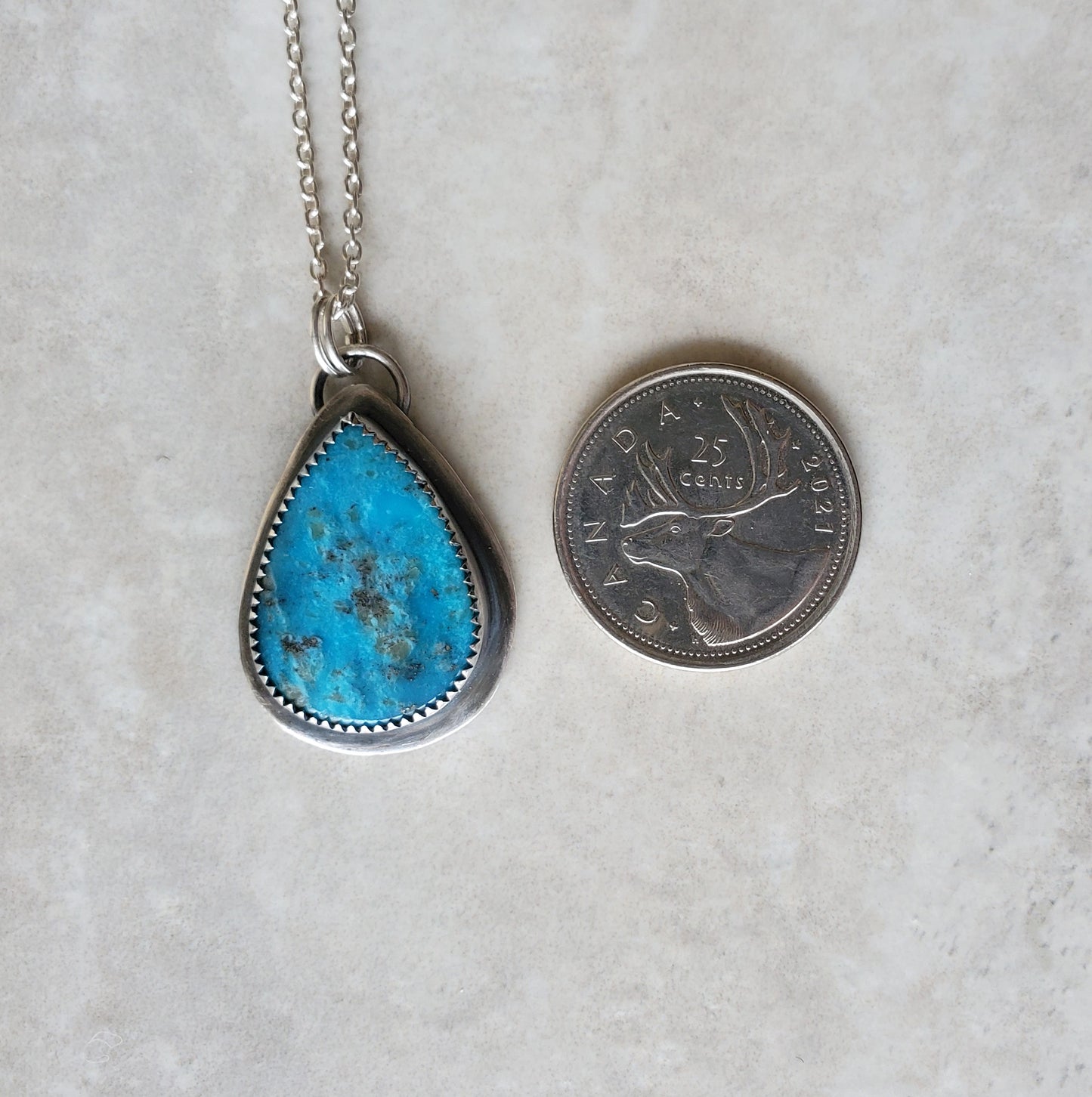 Arizona turquoise silversmith necklace beside a quarter