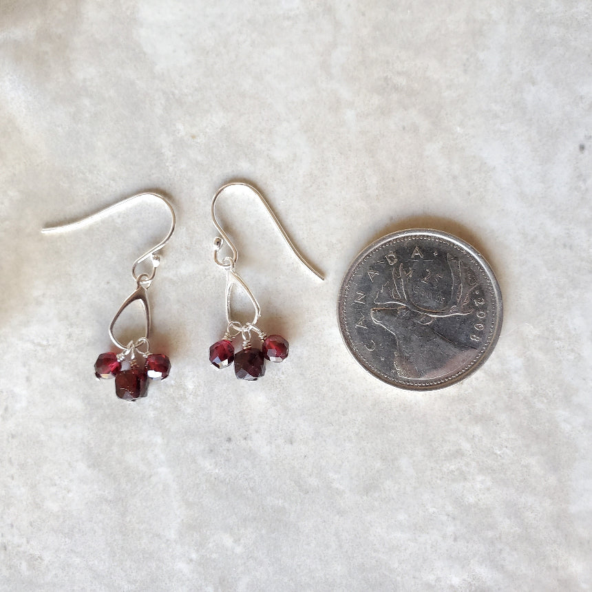 Faceted Garnet dangle earrings beside a quarter