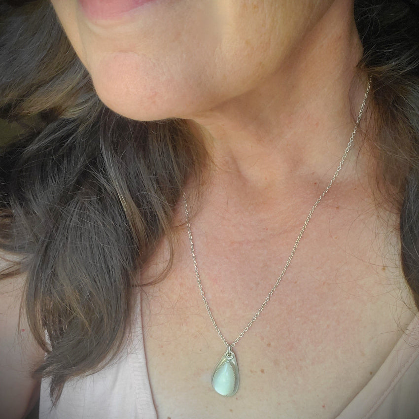 Close-up of a person wearing a Moonstone silversmith pendant necklace