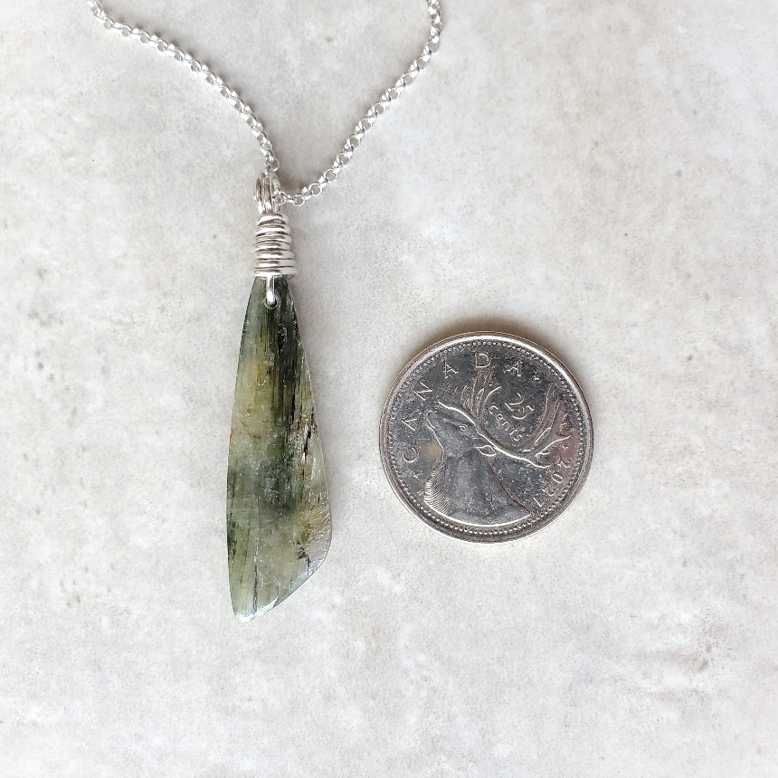 Green Kyanite freeform pendant necklace beside a quarter