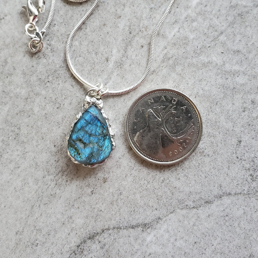 Blue Labradorite teardrop pendant necklace beside a quarter