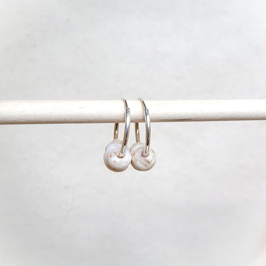 Pair of silver hoop earrings with shells on a white background