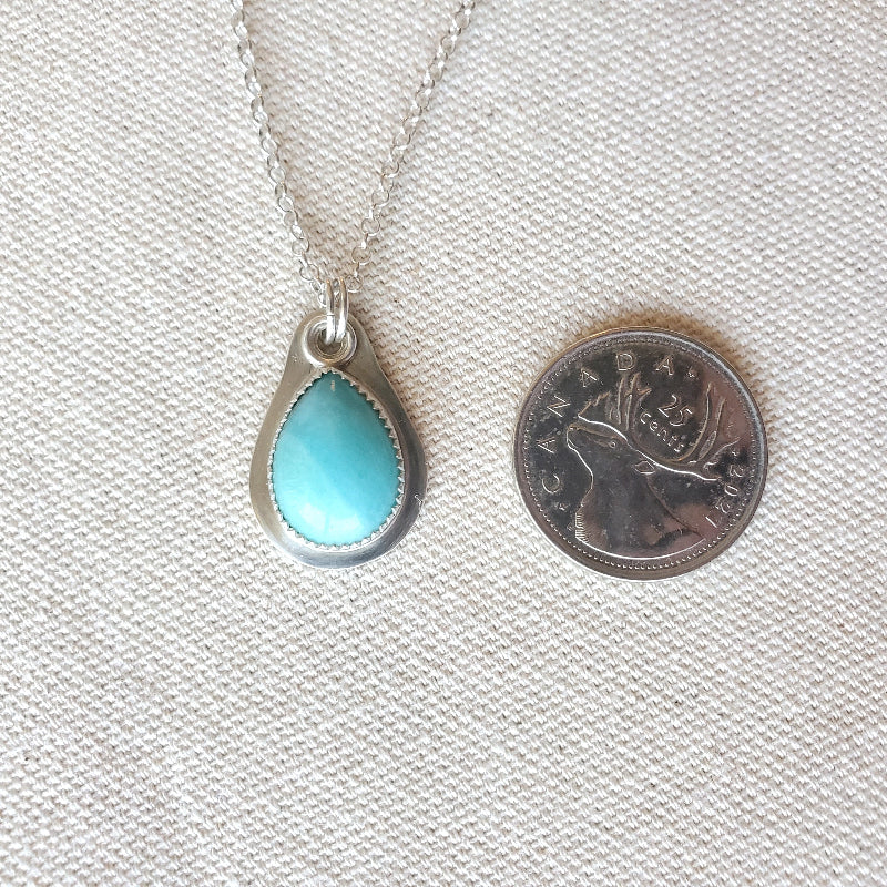 Amazonite teardrop silversmith necklace beside a quarter