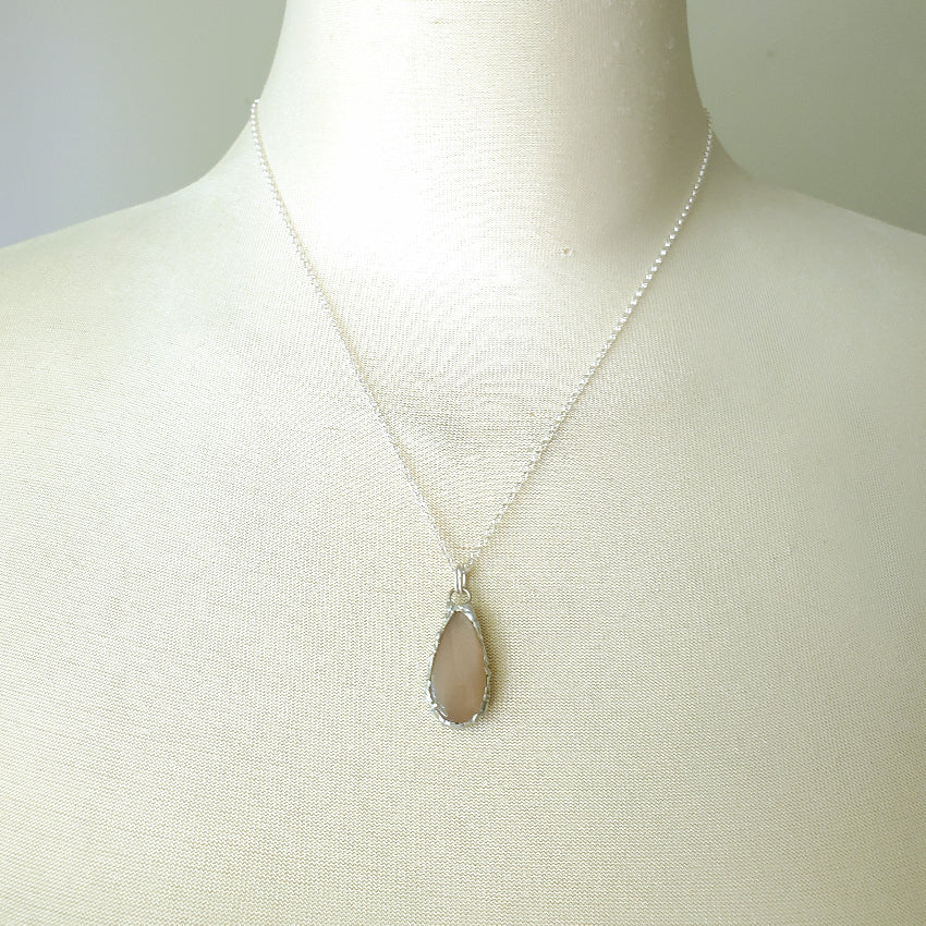 Necklace with a teardrop Peach Moonstone pendant on a mannequin