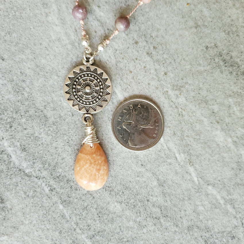 Necklace with a pendant and Pink Aventurine teardrop next to a quarter
