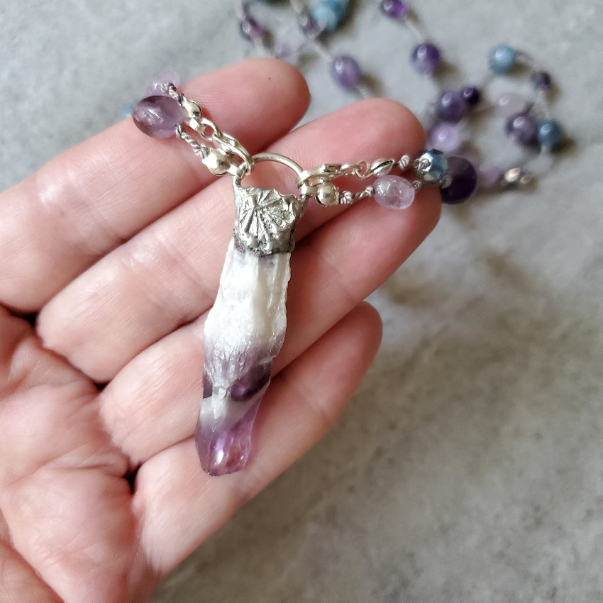 Hand holding an Amethyst and Aquamarine necklace