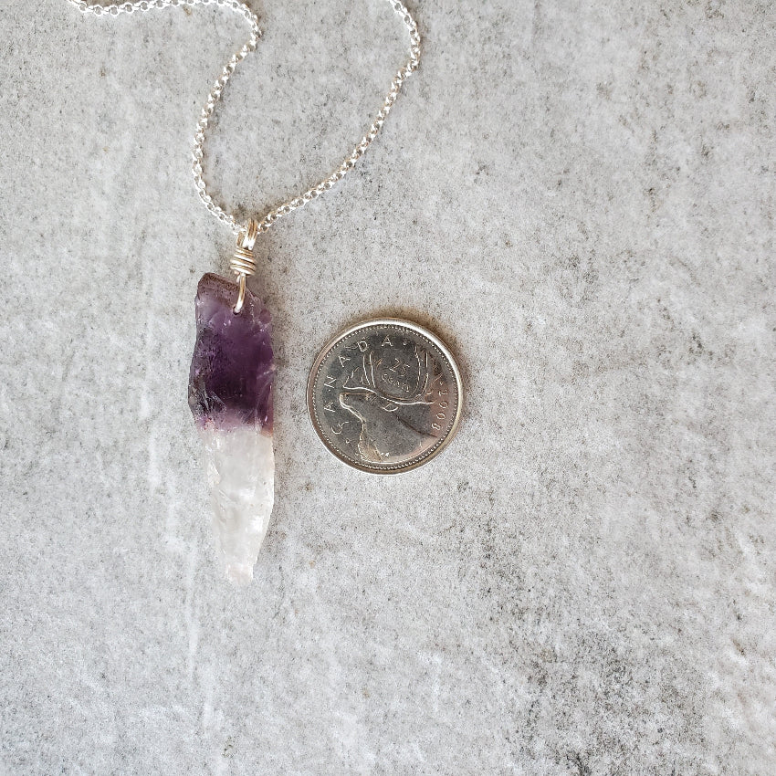 Chevron Amethyst point pendant necklace beside a quarter