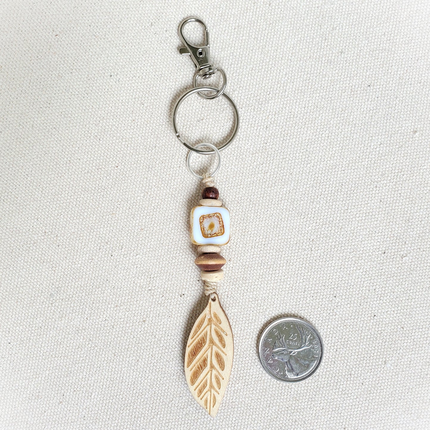 Keychain with feather charm and bead on a light gray background