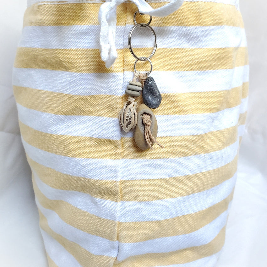Yellow and white striped bag with a keychain featuring seashells on a white background