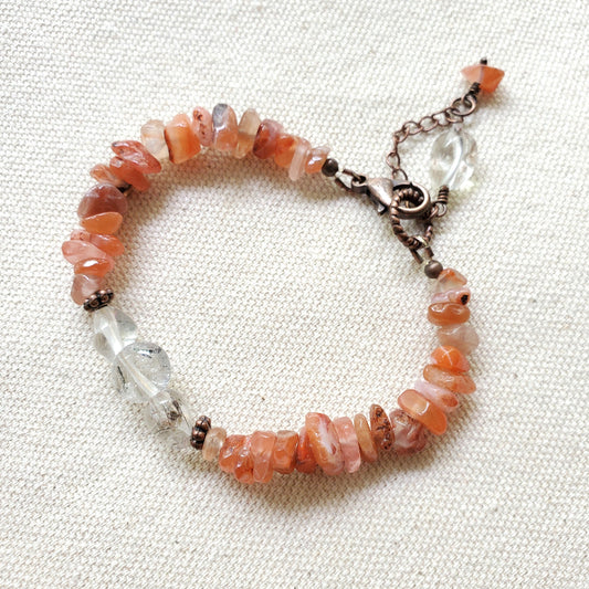 Bracelet with orange and clear beads on a textured fabric background