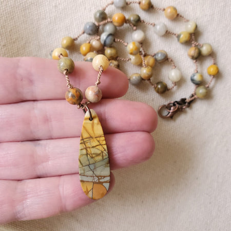 knotted Crazy Lace Agate necklace with Picasso Jasper focal in hand