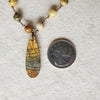 knotted Crazy Lace Agate necklace with Picasso Jasper focal beside quarter