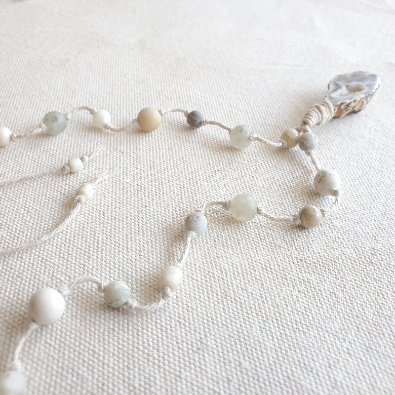 Necklace with white and gray beads on a light fabric background
