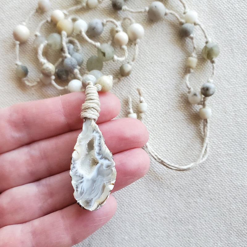 Necklace with a pendant held by a hand on a light background