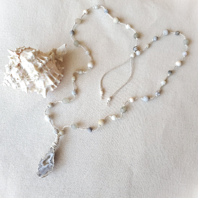 Necklace with white and gray beads on a beige fabric background
