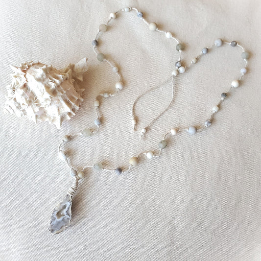 Necklace with white and gray beads on a beige fabric background
