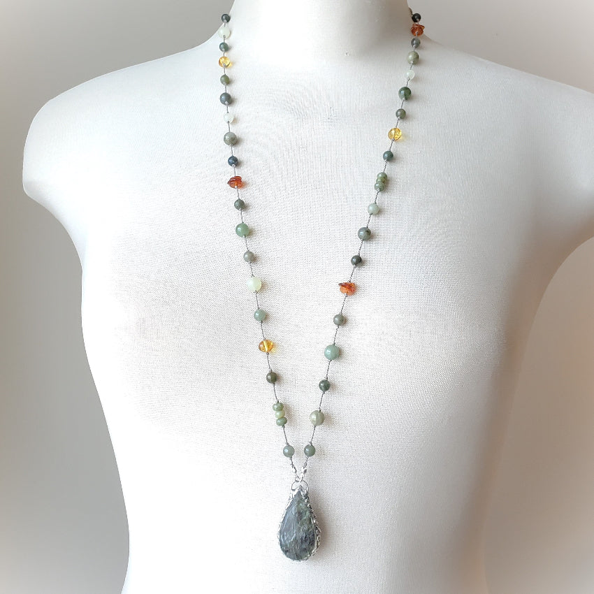 Necklace with multicolored beads and a teardrop pendant on a mannequin.