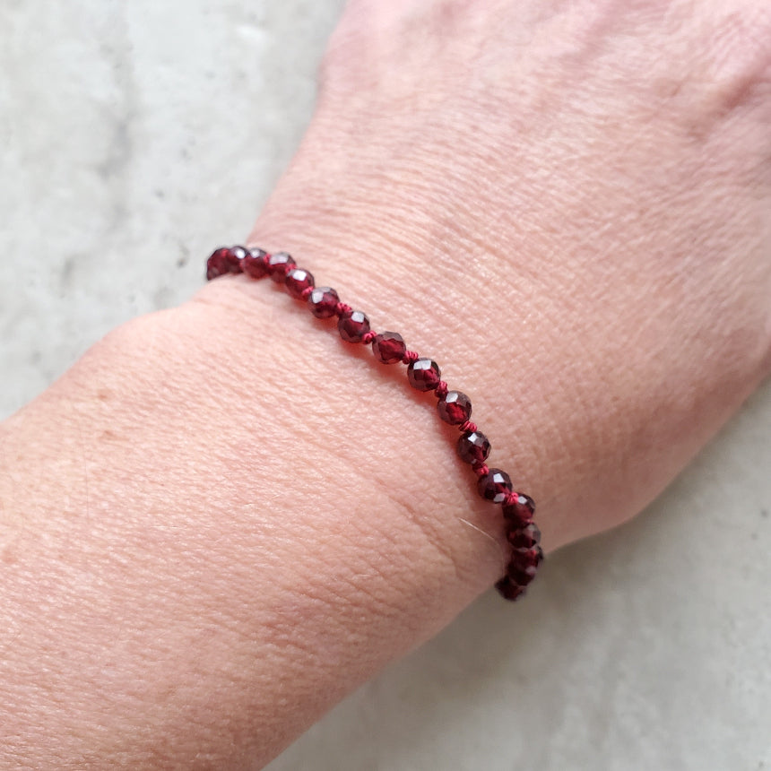 Garnet beaded bracelet on a wrist with a light background