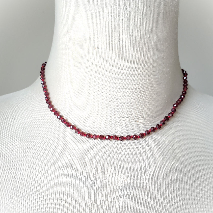 Faceted Garnet necklace on a mannequin with a plain background