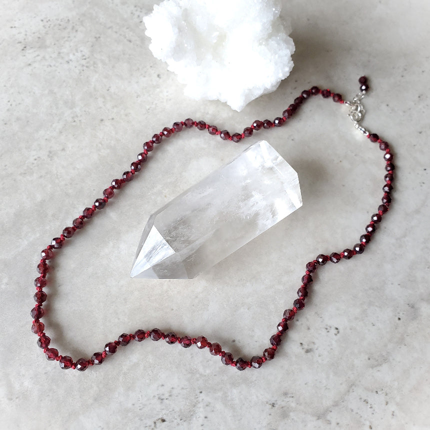 Faceted Garnet necklace on a light gray surface