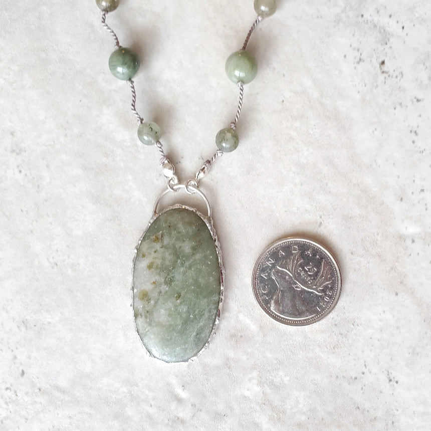 Beaded gemstone necklace beside a quarter