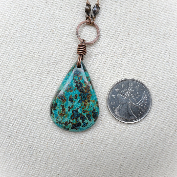 Chrysocolla gemstone pendant beside a quarter