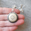 Round fossil coral silversmith pendant in hand