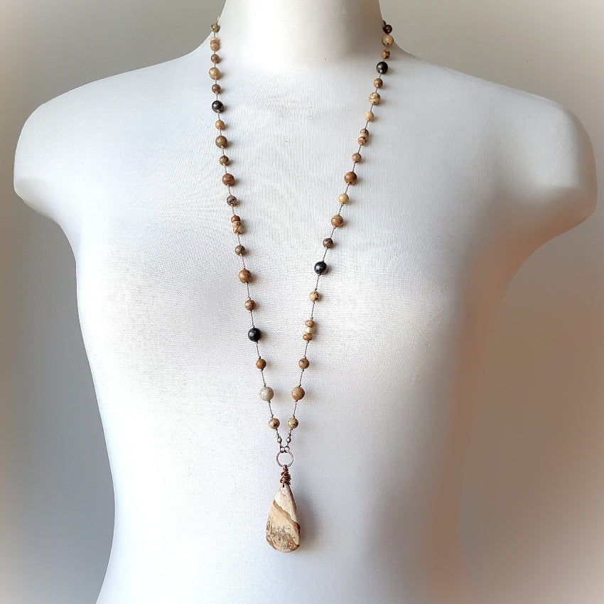 Necklace with brown and beige beads on a mannequin against a neutral background