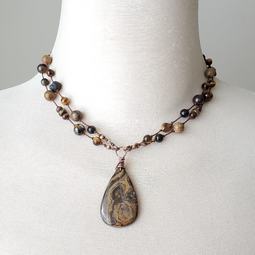 Necklace with a teardrop pendant on a mannequin bust against a plain background