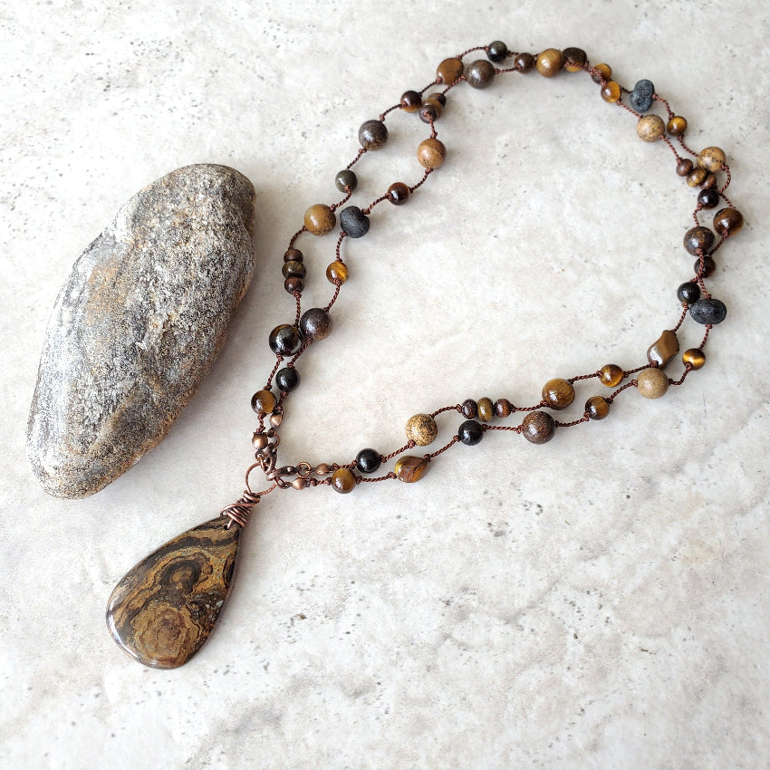 Beaded necklace with a large pendant on a textured surface