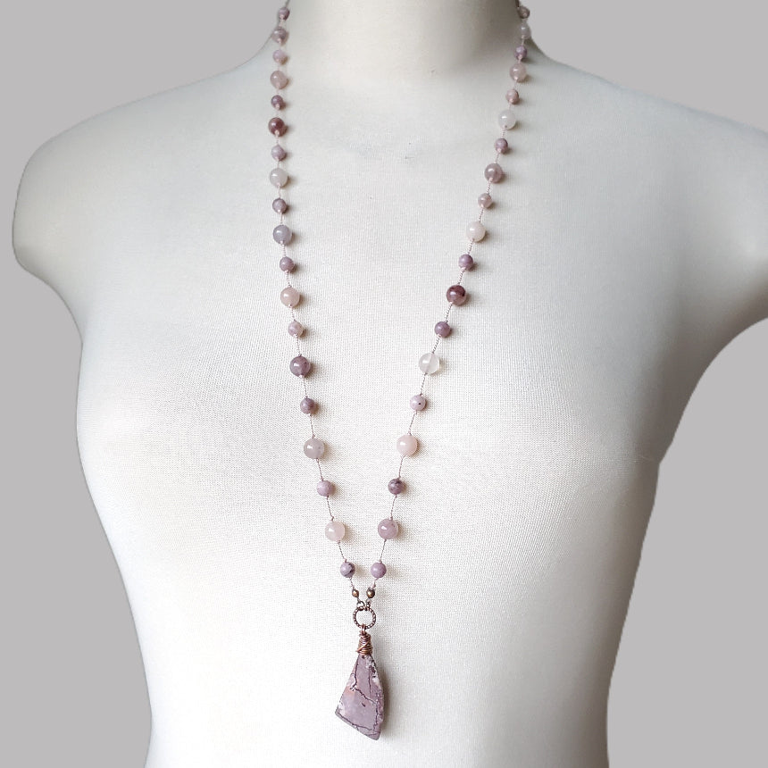 Necklace with pink beads and a pendant on a mannequin against a white background