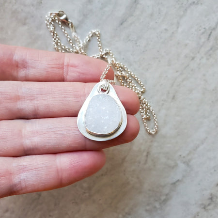 White druzy agate silversmith pendant in hand