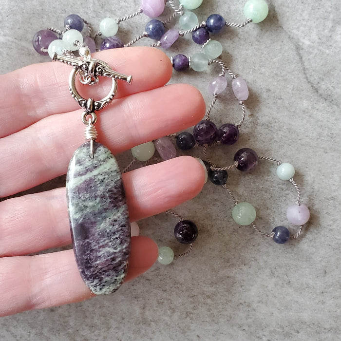 Purple and Green gemstone knotted necklace in hand