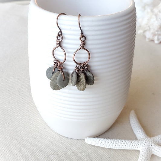 Copper and stone earrings on a white ceramic cup with a starfish