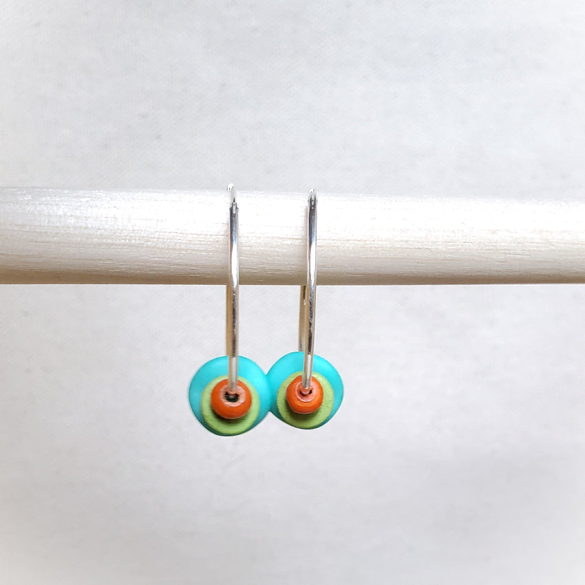 Pair of earrings with colorful circular charms on a white background