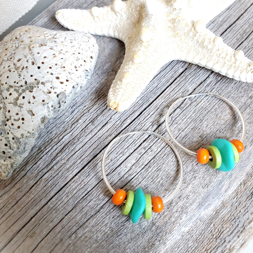 Beaded earrings with colorful beads on a wooden surface with starfish and shell.