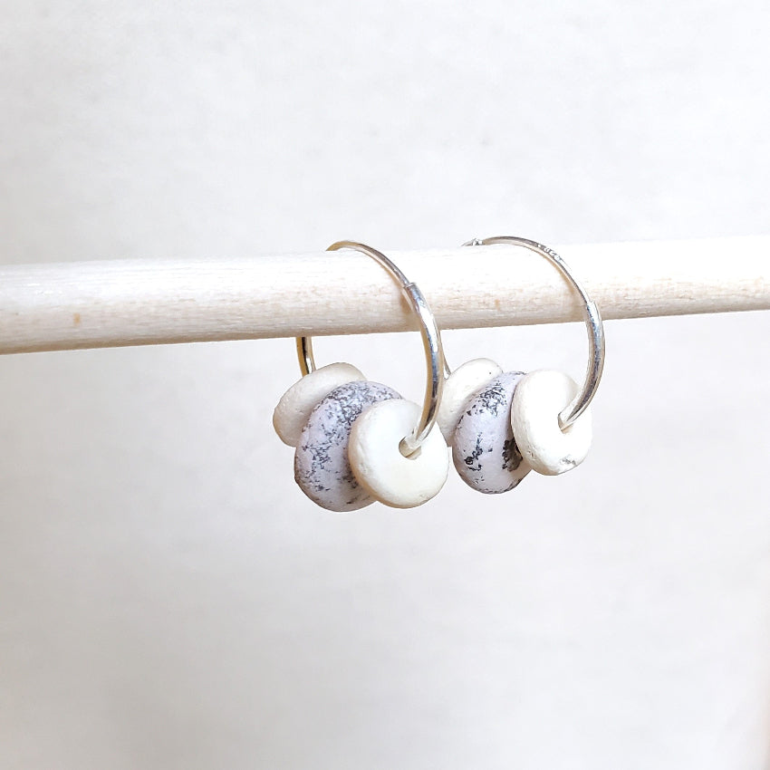 Silver hoop earrings with white beads on a white background