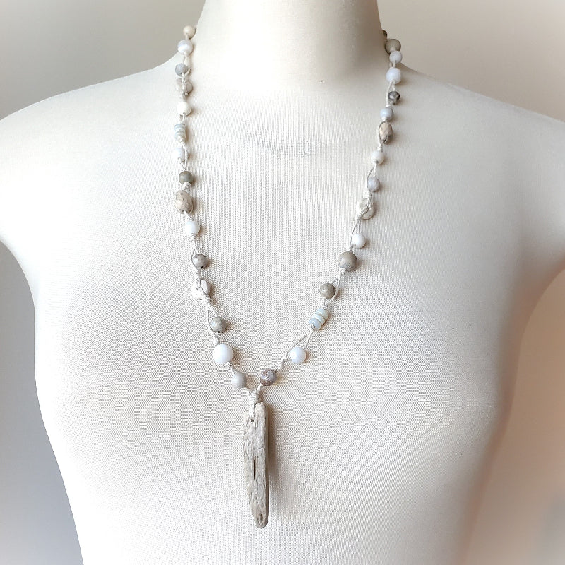 Necklace with a driftwood pendant on a mannequin against a neutral background