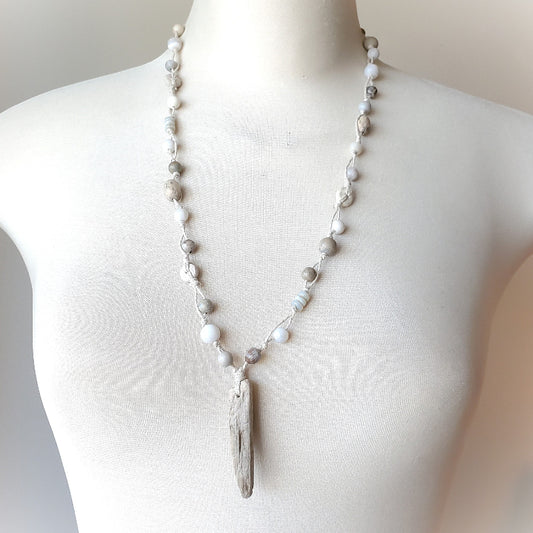 Necklace with a driftwood pendant on a mannequin against a neutral background