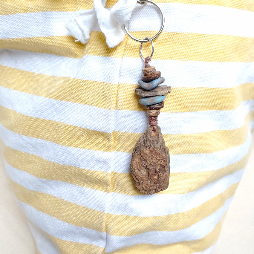 Keychain with natural wood pendant on a yellow and white striped fabric background