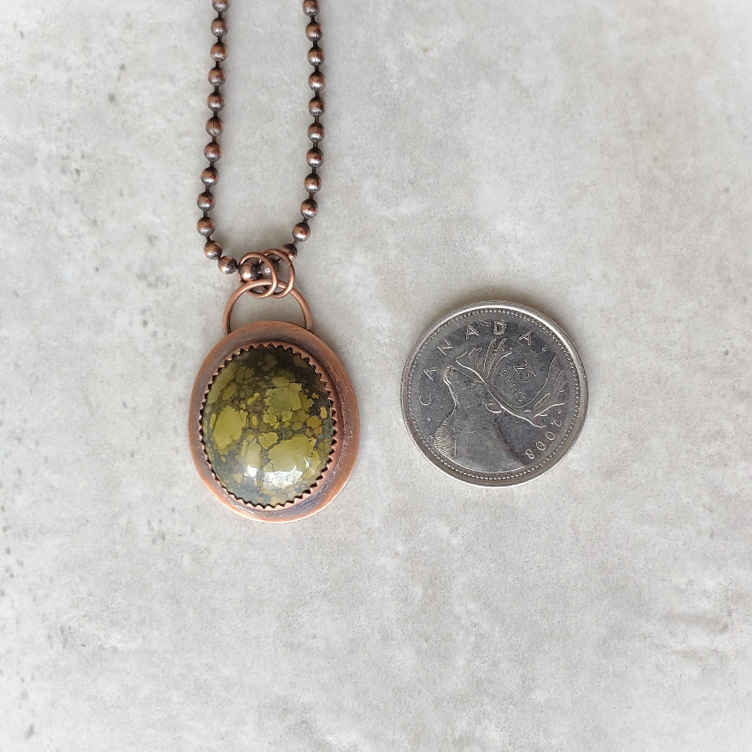 Tibetan Turquoise metalsmith necklace beside a quarter