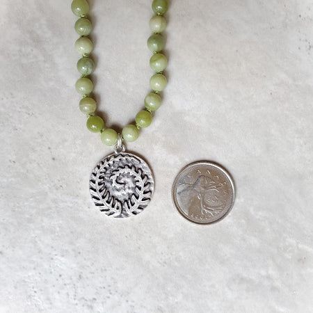 Canadian Jade Knotted necklace with fern focal beside a quarter