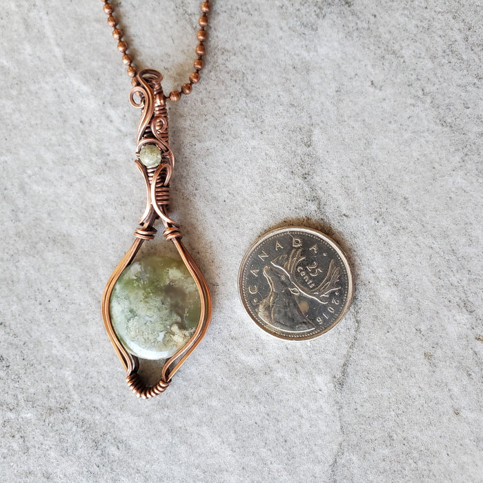 Moss Agate  wire wrapped pendant beside a quarter