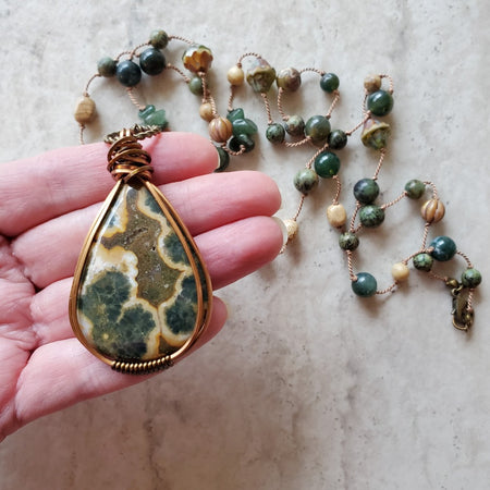 Long beaded gemstone necklace with Ocean Jasper focal in hand 