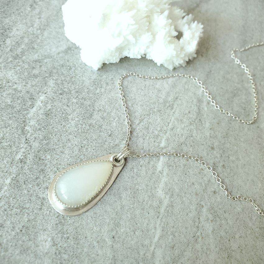 Moonstone silversmith teardrop pendant Necklace on a textured surface