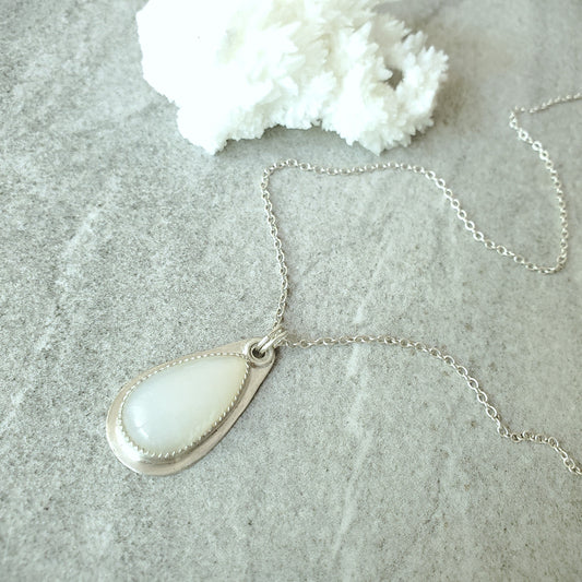 Moonstone silversmith teardrop pendant Necklace on a textured surface