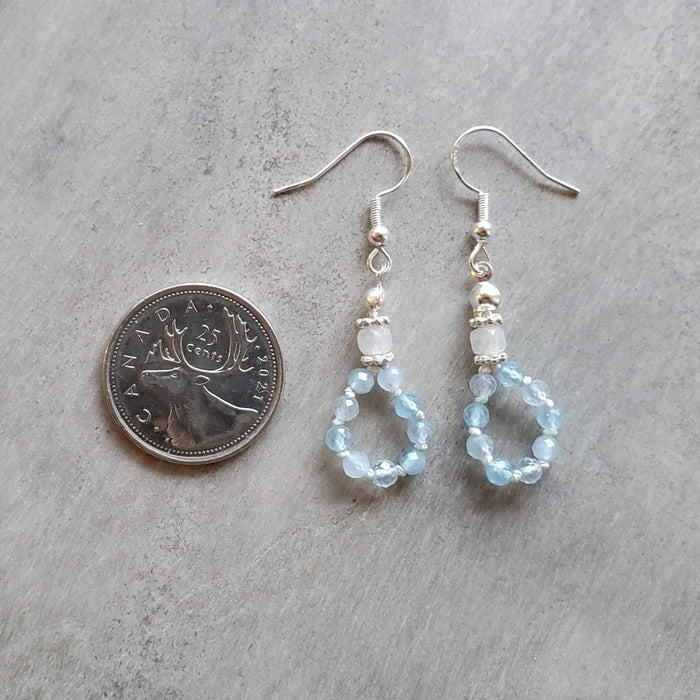 silk knotted Aquamarine and moonstone earrings beside a quarter