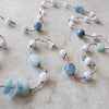 Aquamarine and crystal long hand knotted necklace close up on tile