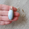 Blue Opal oval pendant set in silver in hand